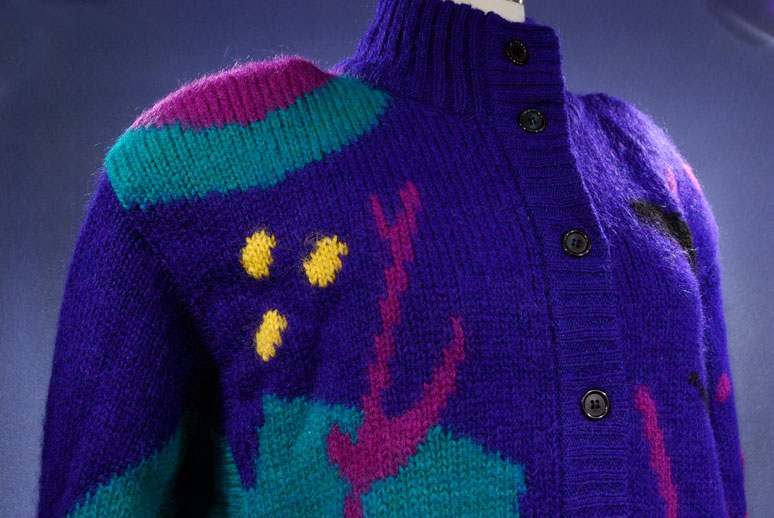 Woman's brightly colored wool sweater-coat with desert motif and button-up front in purple, green, and yellow