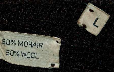 Close-up of clothing labels showing 50% mohair 50% wool fabric on a men's retro striped cardigan sweater by Sears