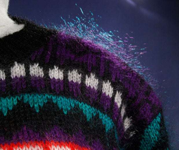Close-up of woman's black multi-color striped mohair crewneck sweater with purple, teal, and white accents in medium size