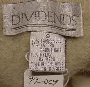 Close-up of Dividends brand label showing fabric content of woman's tan argyle angora-lambswool sweater