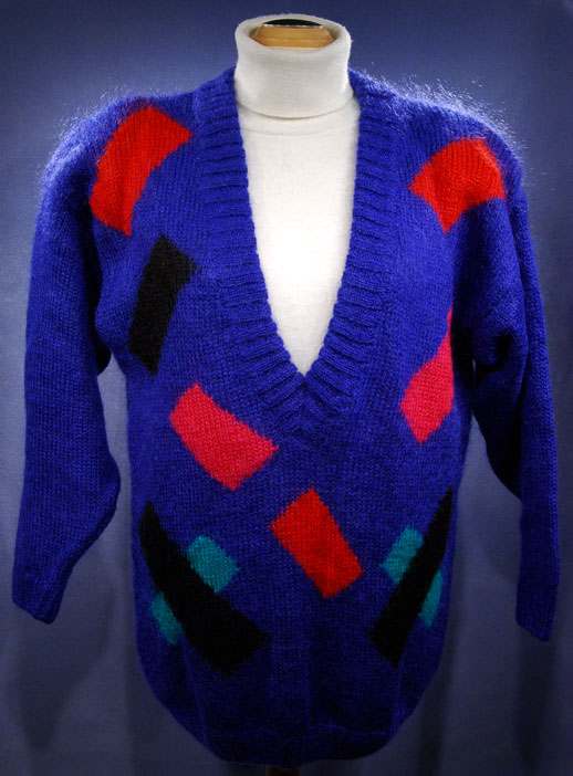 Woman's colorful deep V-neck jewel-tone sweater with red, black, and green geometric design by Nell Flowers