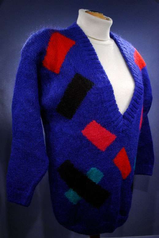Woman's colorful deep V-neck jewel-tone sweater with red, black, and green geometric design by Nell Flowers