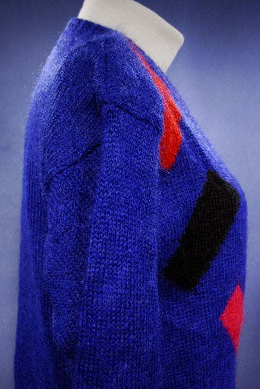 Woman's colorful deep V-neck jewel-tone sweater with red, black, and green geometric design by Nell Flowers