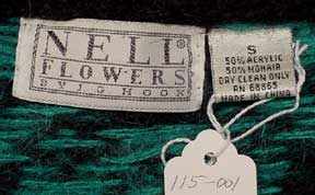 Close-up of Nell Flowers label on a woman's retro green and black mohair-blend cardigan sweater, size 50 plus-sized with care tags
