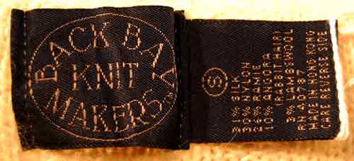 Black fabric label with Back Bay Knit Makers logo and garment care instructions for woman's white silk-cotton-angora sweater vest.