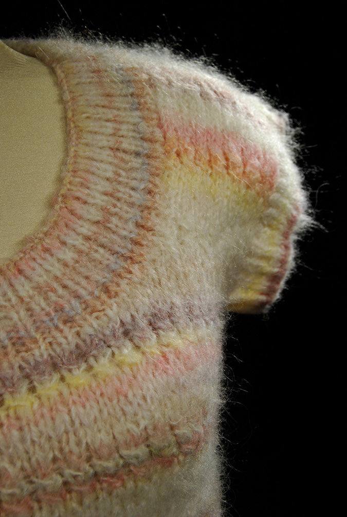 Close-up of a hand-knit round-neck sleeveless pastel striped sweater vest for women or girls in X-Small size