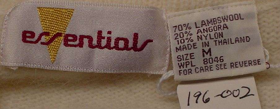 Essentials brand label on woman's white angora lambswool sweater-shirt detailing fabric and size information