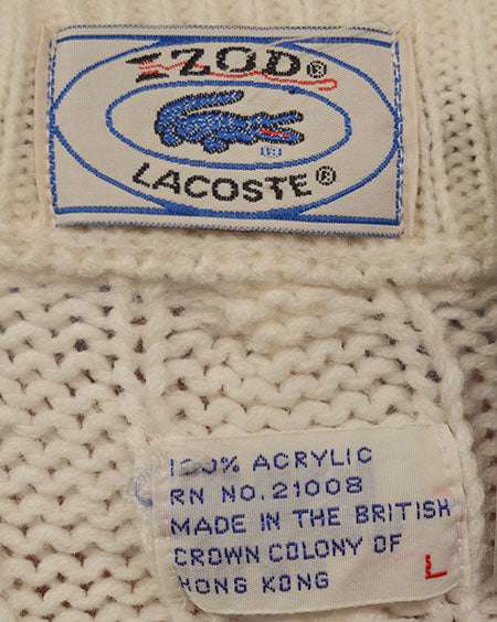 Close-up of Izod Lacoste label and fabric texture on men's classic retro cable-knit tennis sweater made of 100% acrylic