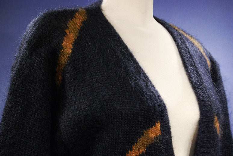 Woman's long black mohair blend cardigan with metallic gold crest design on mannequin