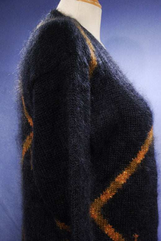 Woman's long black mohair blend cardigan with metallic gold crest design shown from side on mannequin