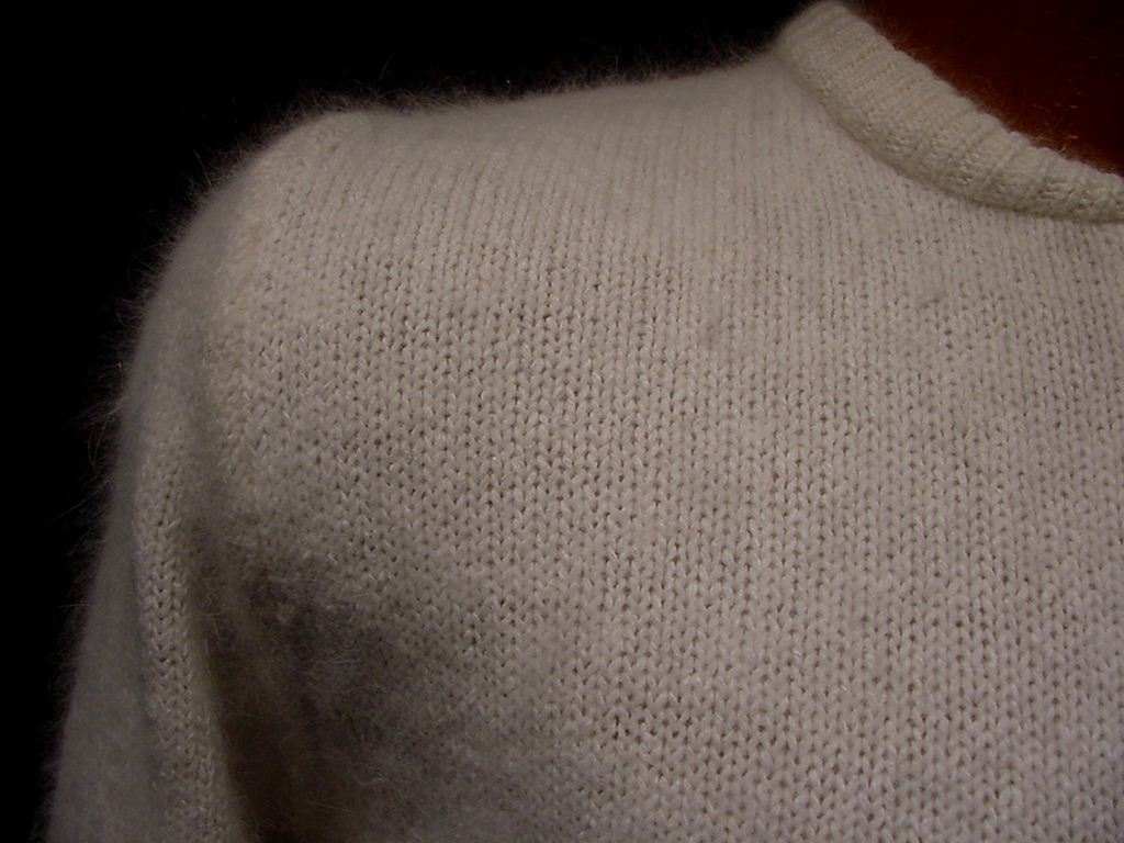 Close-up of soft natural white silk-angora fabric for teen girl's cropped zipper-front cardigan sweater