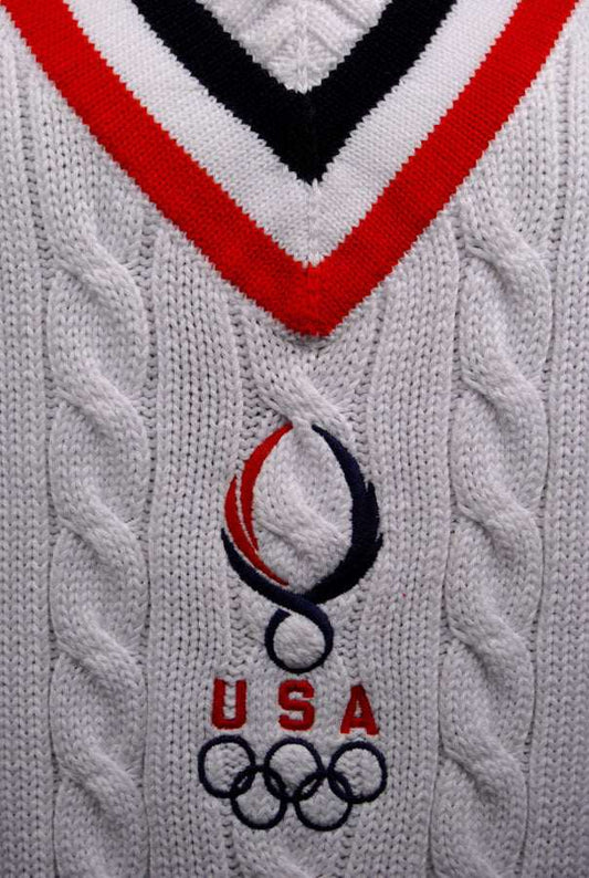 White sleeveless cable-knit tennis sweater vest with USA Olympic emblem and red and navy V-neck trim