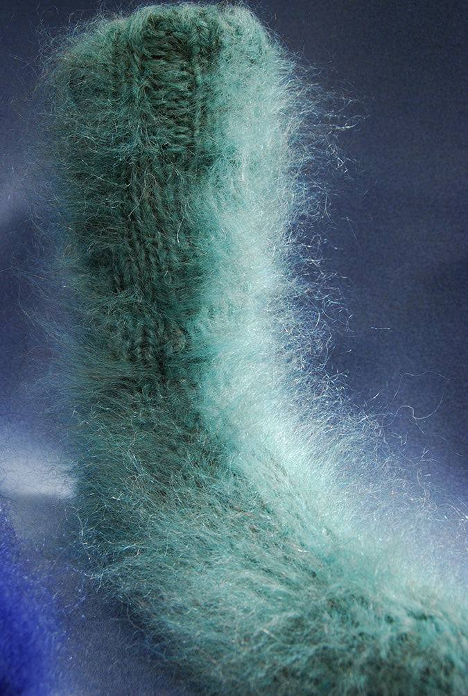 Thick warm hand-knit fuzzy mohair sock in green against dark background