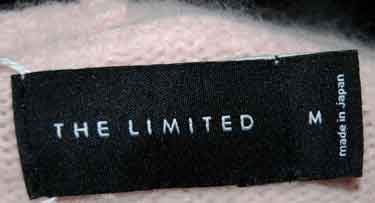 Black clothing label with "THE LIMITED" brand name and size M, made in Japan, on pink fabric