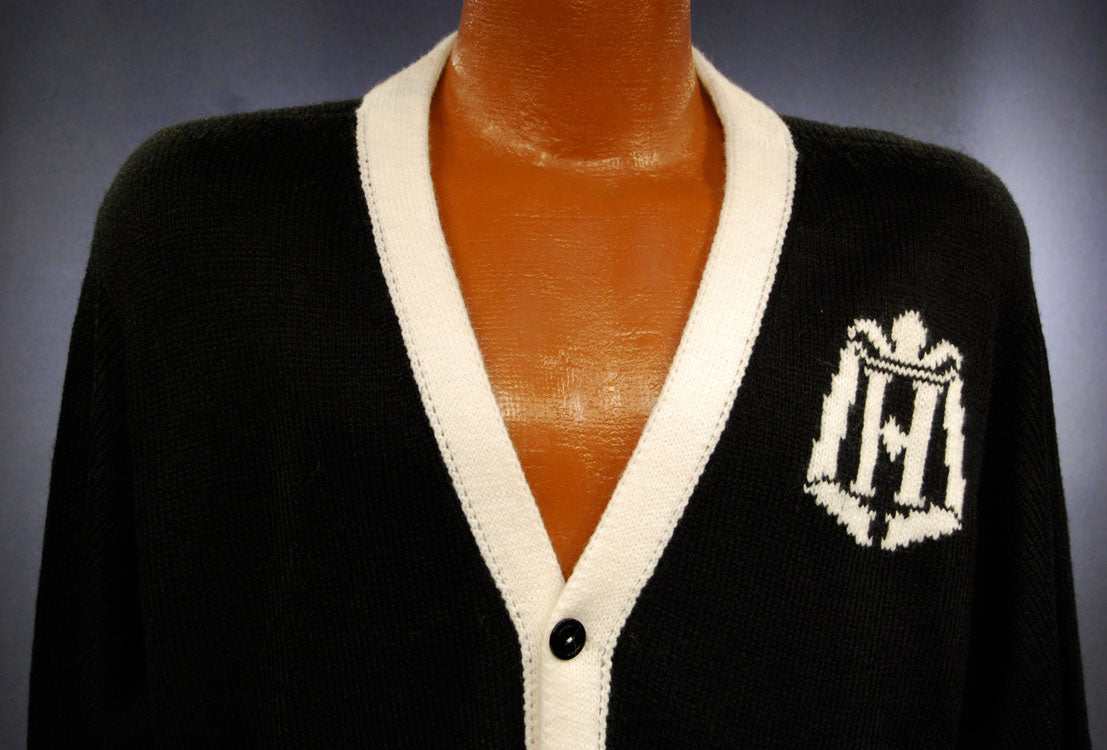 Woman's black cardigan sweater with white trim and tennis racket emblem on front