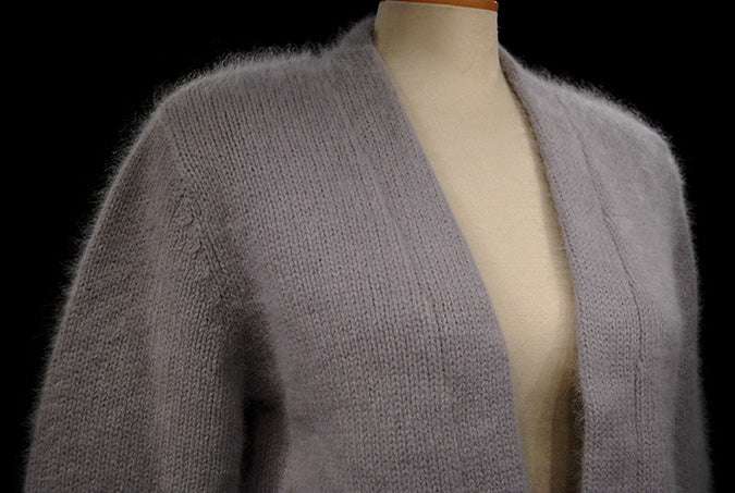 Woman's soft gray angora shrug cardigan with open front and three-quarter sleeves on mannequin