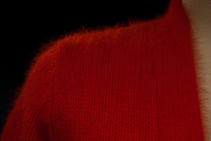 Close-up of red woman's angora shrug cardigan sweater with soft, fuzzy texture and open-front design
