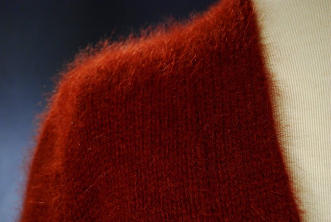 Close-up of soft red woman's angora shrug cardigan sweater with fuzzy texture
