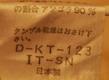 Close-up of the care label on a woman's fancy white angora sweater by Andre Luciano showing fabric composition and washing instructions.