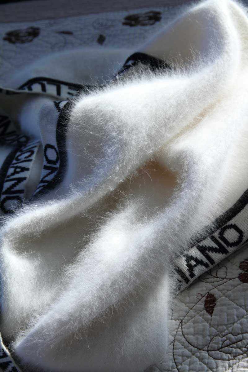 Close-up of woman's fancy white angora sweater with embroidered Andre Luciano trim, size X-small.