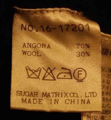 Care label of woman's black angora cardigan showing 70% angora and 30% wool composition with care symbols.
