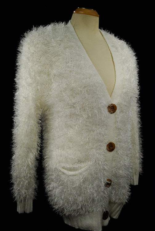 Woman's eyelash cardigan sweater with long fuzzy acrylic fibers, imitation rabbit fur, four buttons, and front pockets in off-white color.