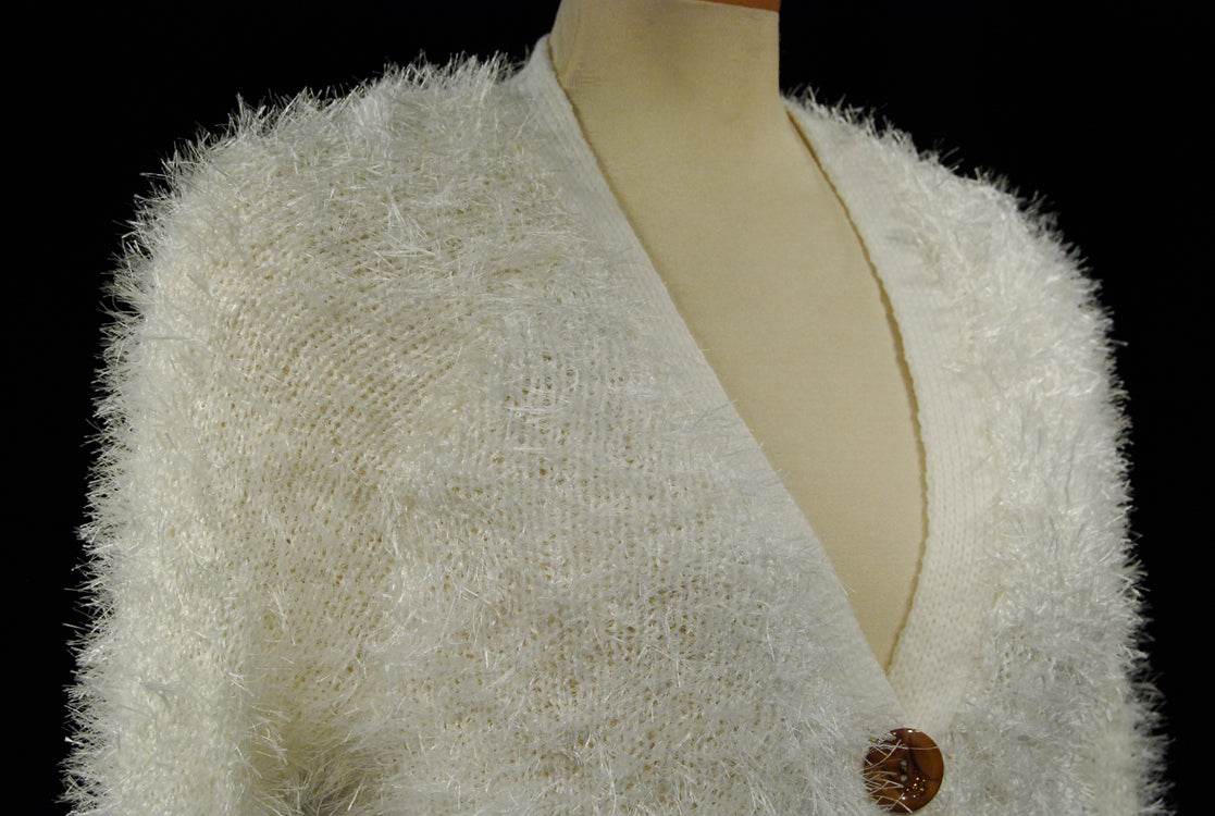 White woman's eyelash cardigan sweater with long fuzzy acrylic fibers and four buttons on mannequin