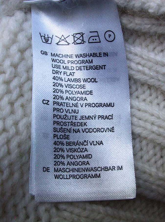 Ivory sleeveless angora lambswool cable-knit sweaterdress care label with fabric composition and washing instructions