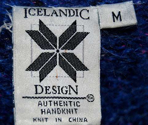 Close-up of Icelandic Design label on woman's medium blue speckled mohair sweater showing authentic handknit details.