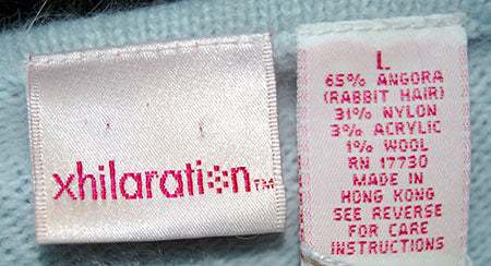 Close-up of powder blue Woman's Angora Tie-Neck Sweater label by Xhilaration showing fabric content and size L.
