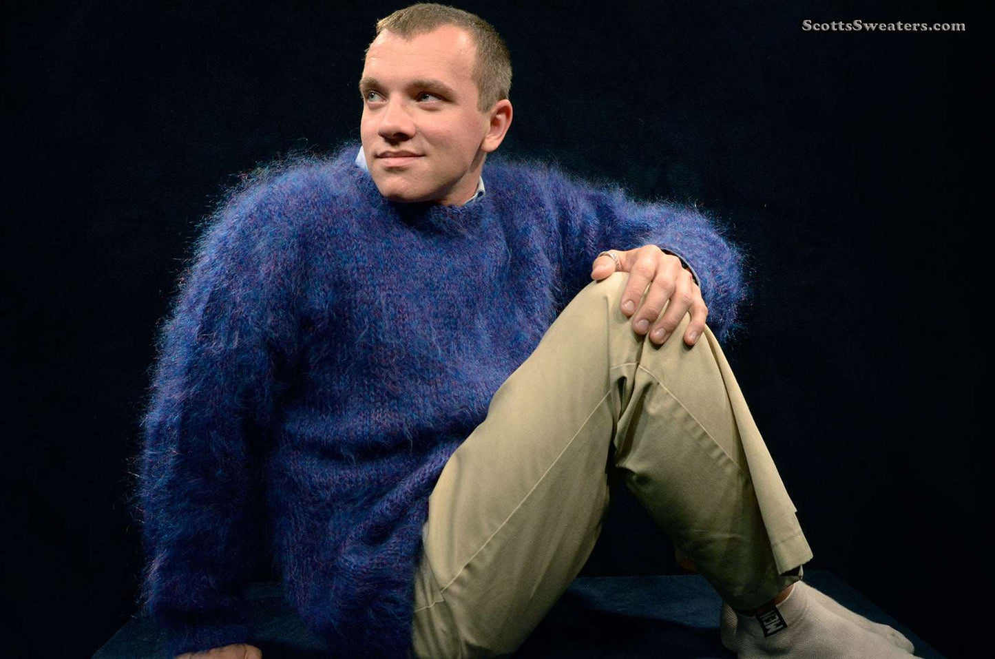 Men's navy-blue crewneck Scottish mohair sweater by Lairds of Scotland worn by seated male model