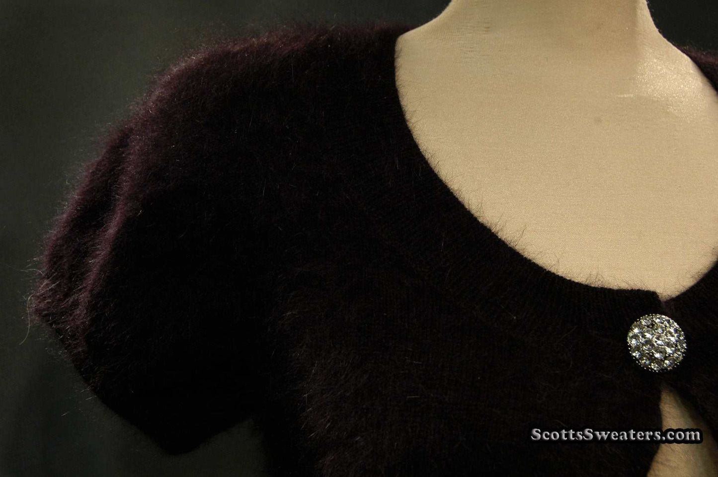 Woman's black angora shrug cardigan with jeweled rhinestone button by Express on mannequin