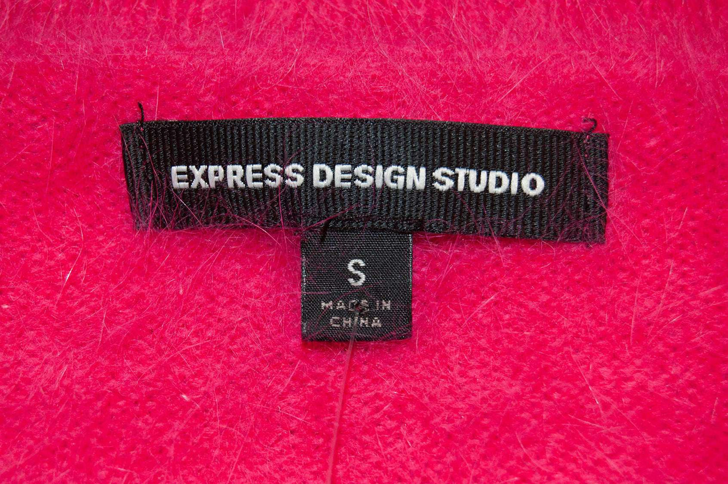 Close-up of Express Design Studio label on bright pink Woman's Angora Shrug cardigan sweater