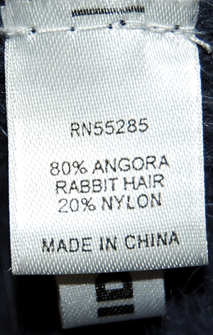 Close-up of a clothing label showing fabric composition of 80% angora rabbit hair and 20% nylon for a woman's angora shrug cardigan by Express.