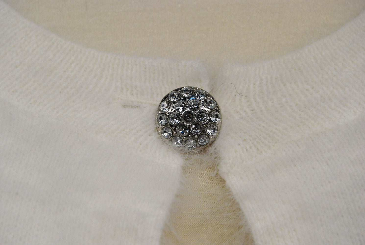 Close-up of jeweled rhinestone button on woman's white angora shrug cardigan sweater by Express