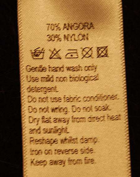 Brown angora and nylon fabric care label for luxurious woman's shawl-collar sweater by Monsoon.