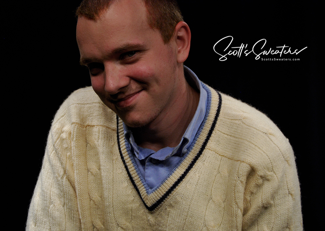 Man wearing retro classic ivory wool cable-knit tennis sweater with navy and French blue striped V-neck trim