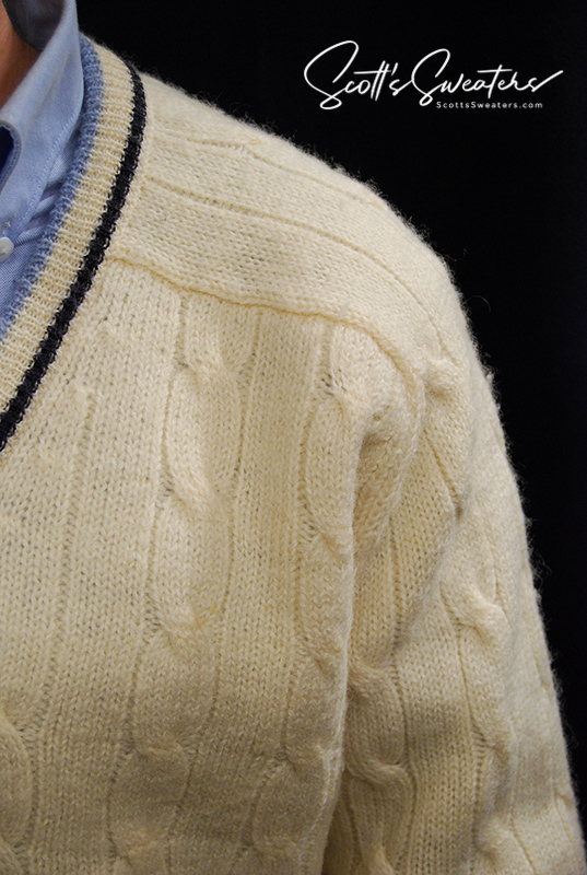 Close-up of original retro classic ivory wool cable-knit tennis sweater with navy and French blue striped trim on collar.