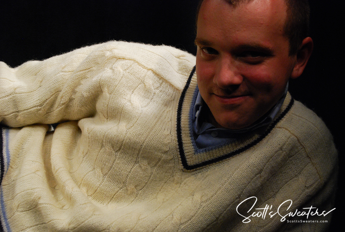 Man wearing retro classic ivory wool cable-knit tennis sweater with navy and French blue striped V-neck trim