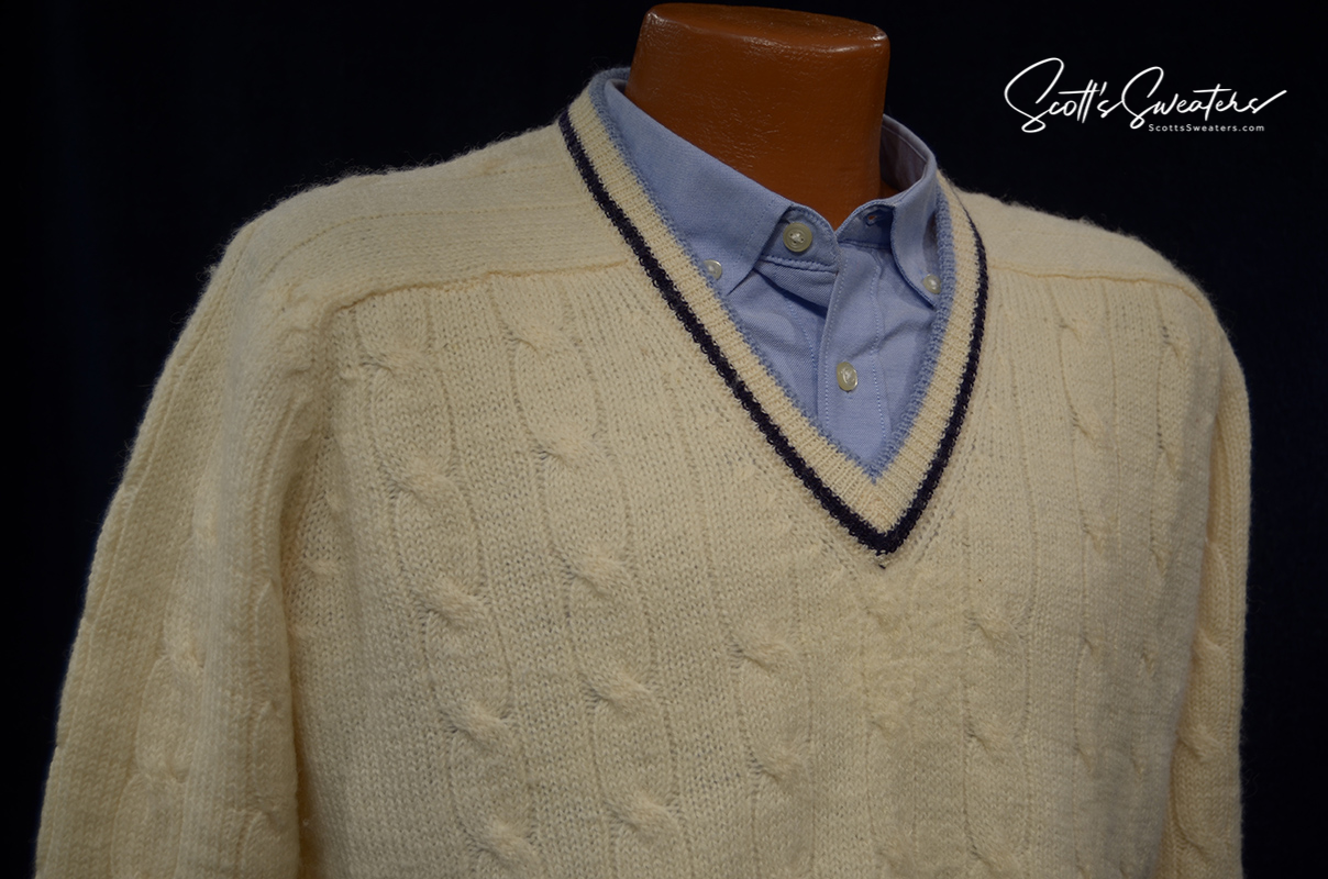 Retro classic ivory wool cable-knit tennis sweater with navy and French blue striped V-neck trim.