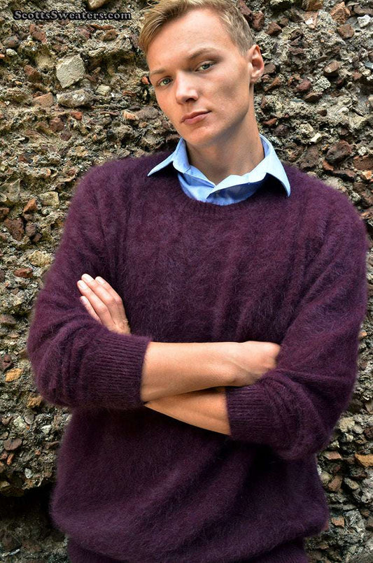 Men's ultra-soft angora crewneck sweater in deep purple worn by model against stone wall background