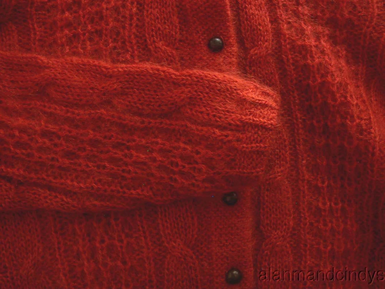 Close-up of red cable-knit woman's retro Italian mohair cardigan sweater with black buttons