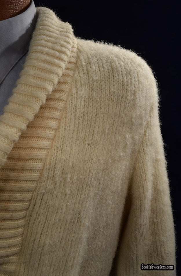 Close-up of a woman's cream-colored Icelandic wool sweater wrap with a ribbed shawl collar and natural thick horizontal lines.