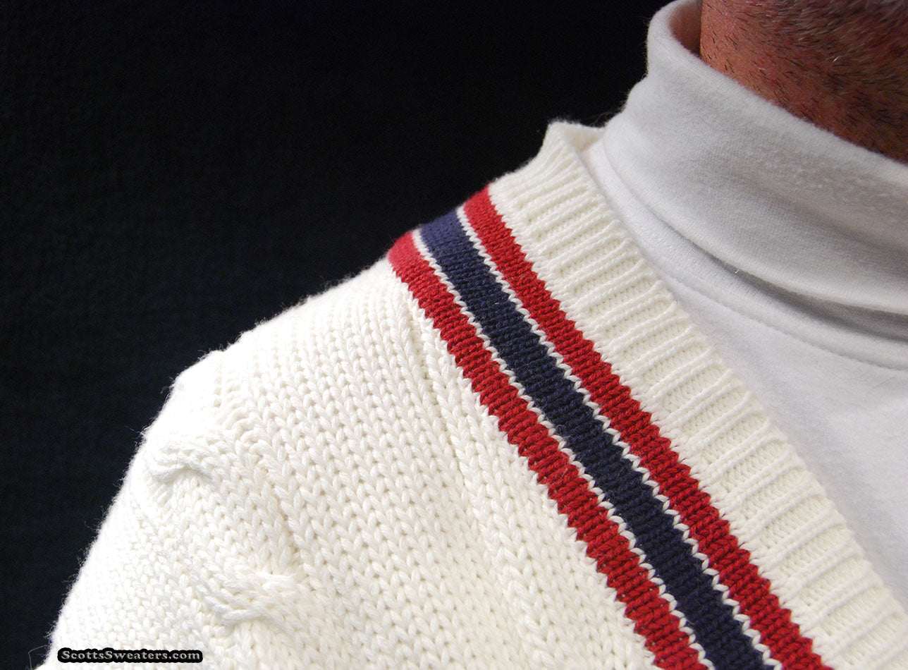 Men's sporty V-neck pullover tennis sweater with red and navy striped trim and cable knit design.