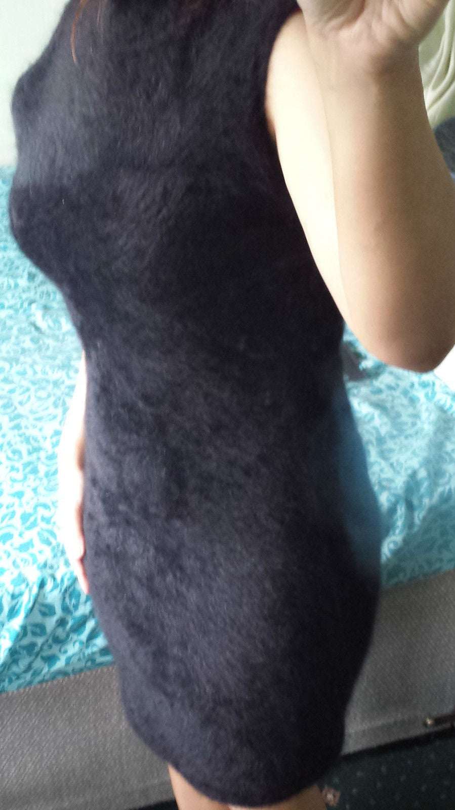 Woman wearing a sleeveless black angora sweaterdress by Next with a cling-fit style