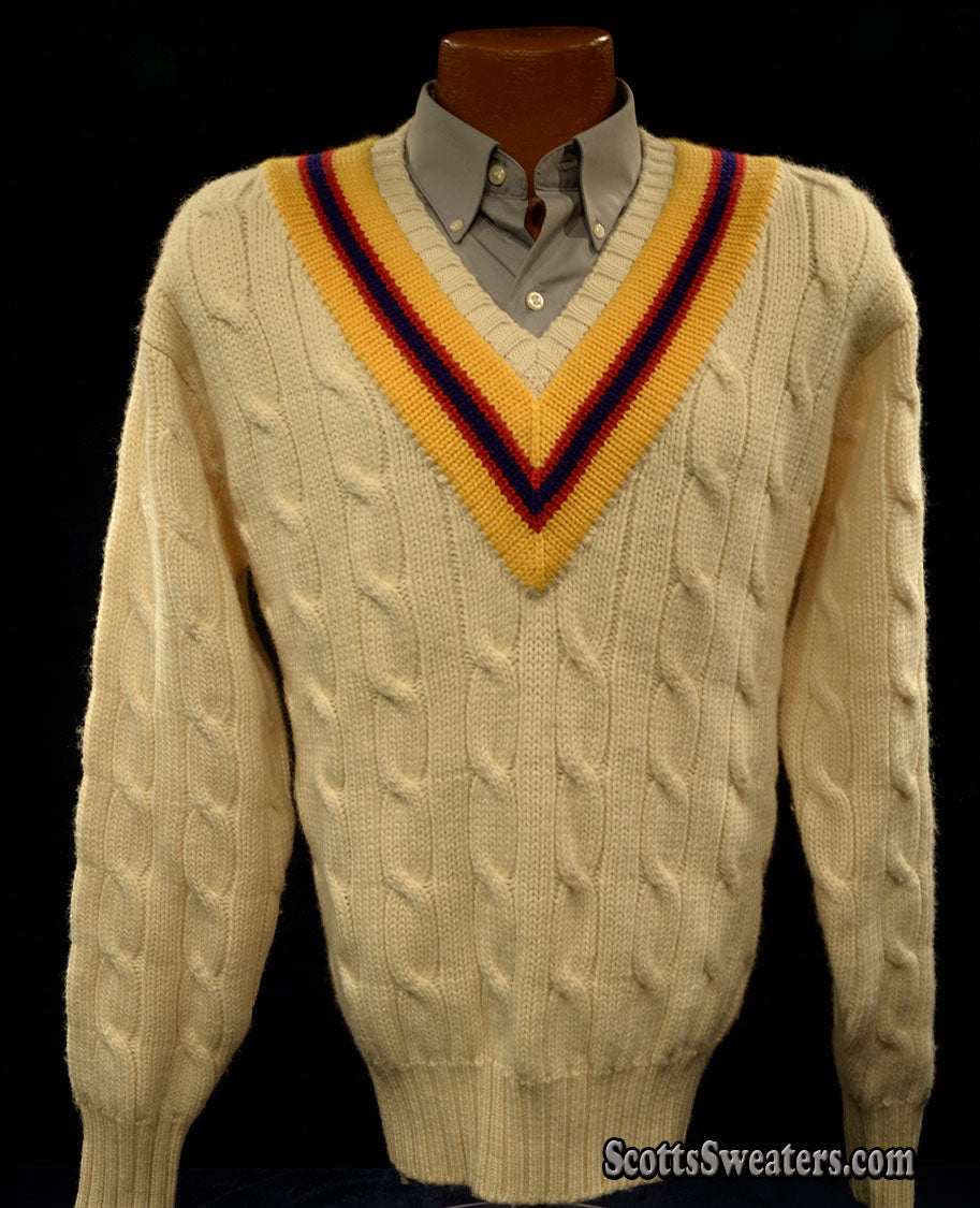 Ivory cable-knit wool tennis sweater with yellow, blue, and red striped V-neck collar.