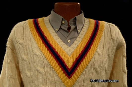 Ivory cable-knit wool tennis sweater with yellow, blue, and red striped V-neck collar on mannequin