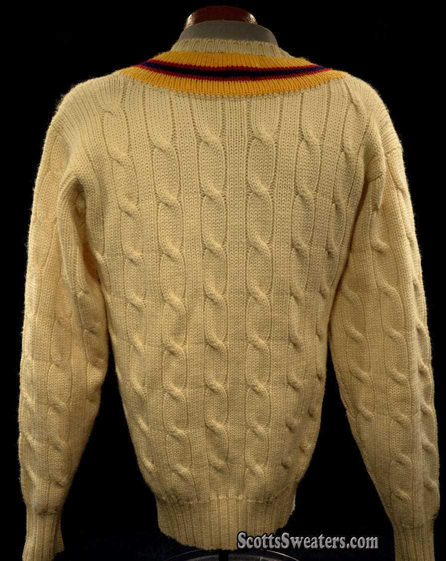 Ivory cable-knit wool tennis sweater with yellow, blue, and red striped neckline, classic thick design.