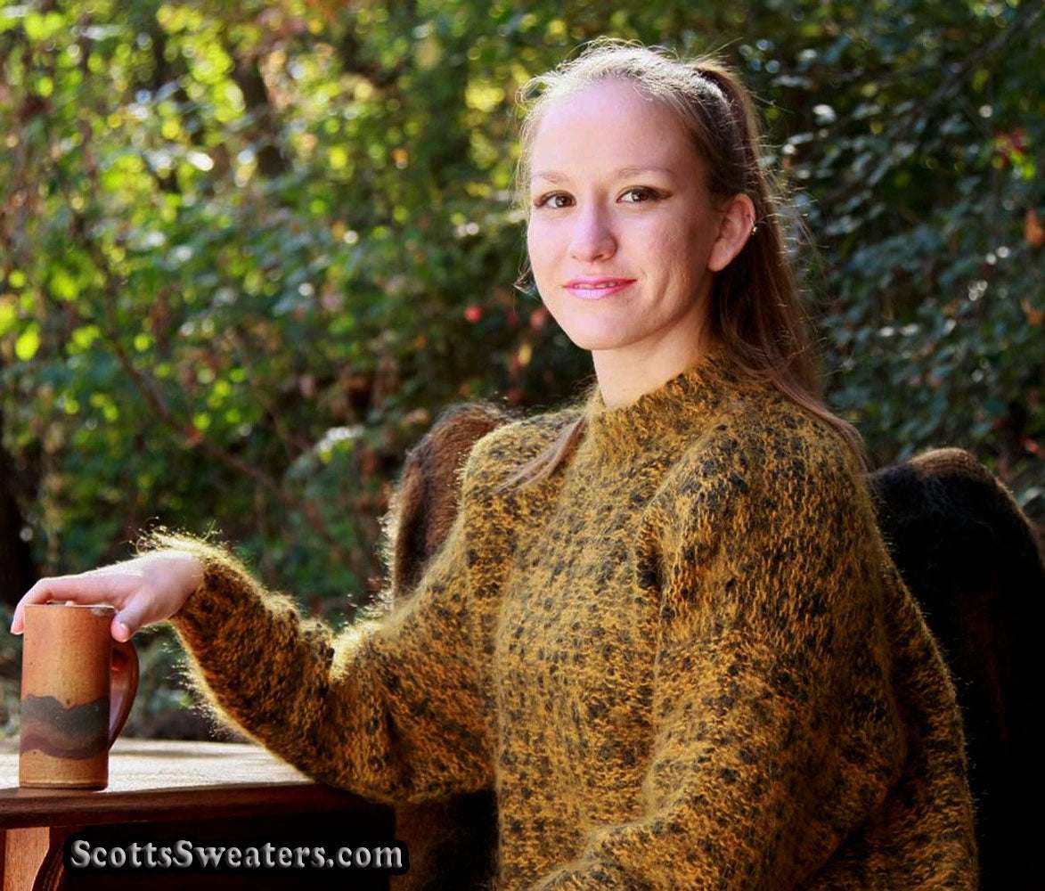 Woman wearing a fuzzy gold and black tweed high crewneck mohair sweater sitting outdoors with a mug