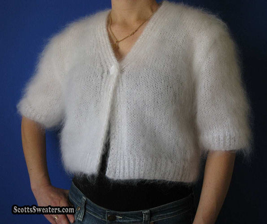 Woman's hand-knitted white mohair shrug with short sleeves on model against blue background